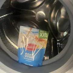 Opakowanie sody oczyszczonej w bębnie pralki, gotowe do czyszczenia szuflady pralki sodą.