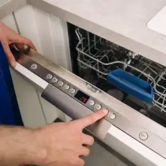 Ręka naciska przycisk na panelu zmywarki Whirlpool, aby zresetować urządzenie.