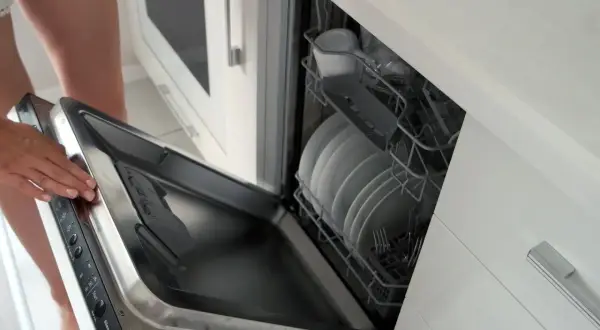 Instrukcja: jak zamontować front do zmywarki Whirlpool. Otwarta zmywarka z koszami pełnymi naczyń.