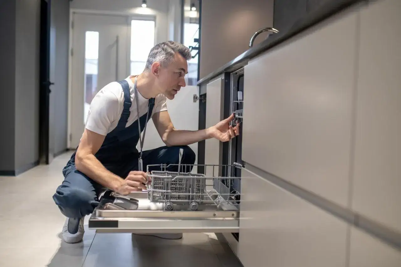 Serwisant sprawdza panel sterowania zmywarki, być może szukając sposobu, jak zresetować zmywarkę Whirlpool.